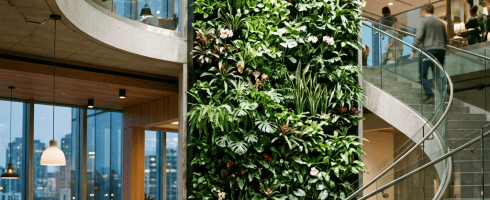 Indoor vertical garden wall beside a spiral staircase in an office lobby