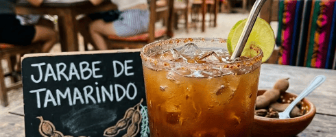 Glass of tamarind syrup drink with ice, lime slice, and chili salt rim