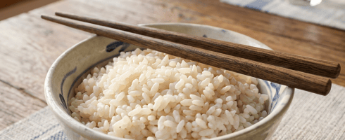 Bowl of steamed white rice with wooden chopsticks resting on top