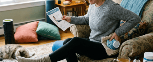 Woman holding ice pack to lower back while reading back pain exercises