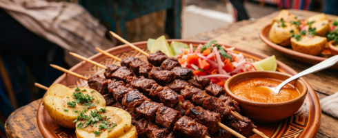 Grilled meat skewers with cooked potatoes, salsa, and dipping sauce on a plate