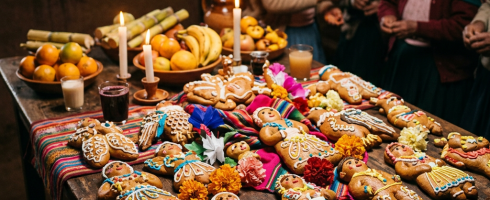 Table with decorated bread figures, fruits, candles, and traditional Day of the Dead offerings
