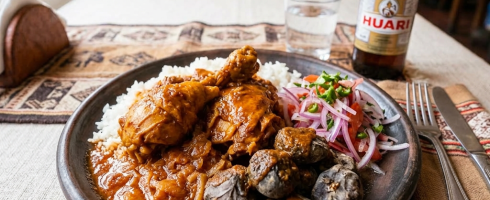 Plate with Peruvian chicken stew, rice, pickled onions, and purple corn