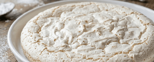White piped meringue cookies arranged on parchment paper on a wooden surface